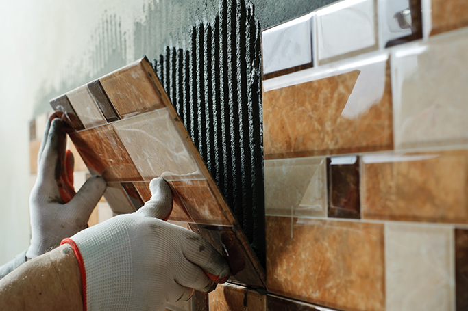 Un obrero coloca azulejos en la pared