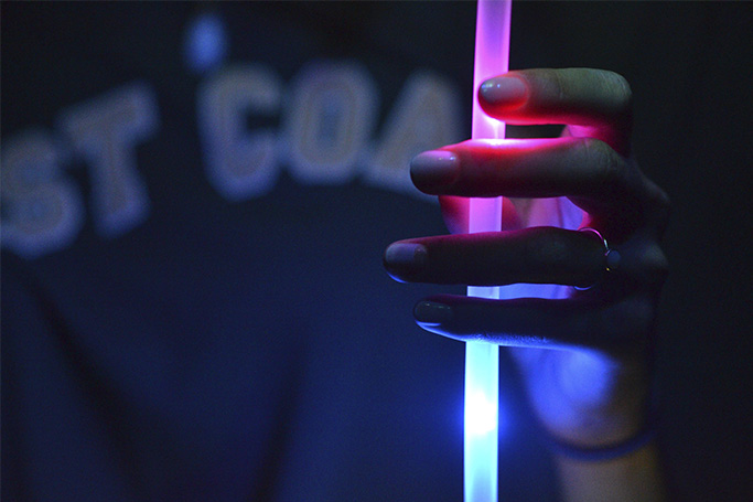 Una persona sostiene una barra de luz química de color morado y azul.