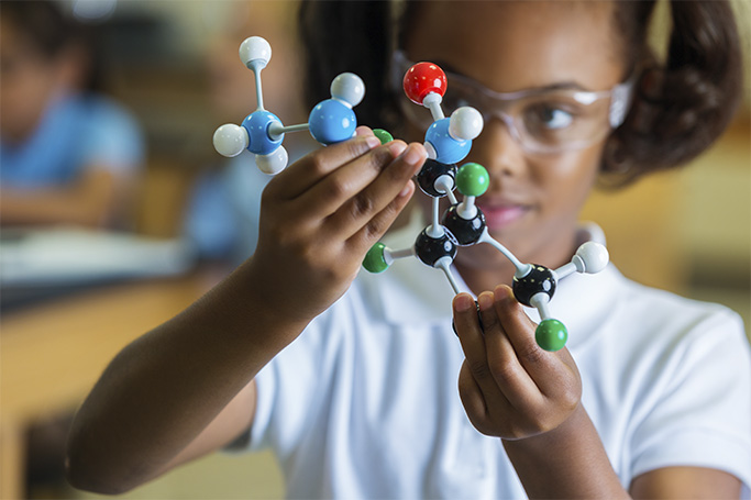 Una niña sostiene un modelo de átomos y moléculas con los que estudiar los diferentes tipos de reacciones químicas