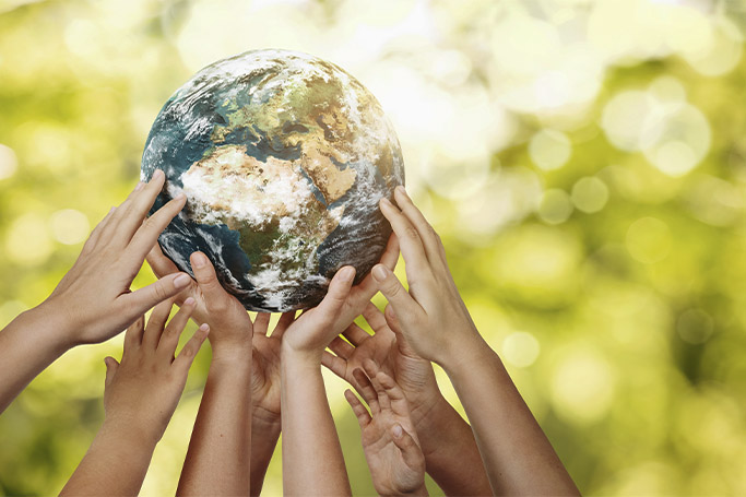 Muchas manos sostienen el mundo, representado por un globo terráqueo en un fondo verde