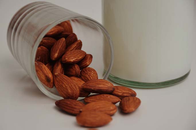 Un vaso de leche y un bote de almendras, dos alimentos ricos en calcio